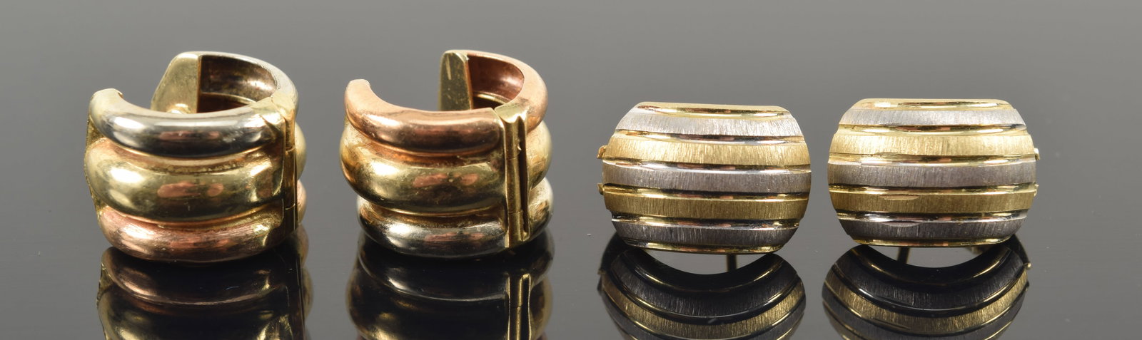 2 pairs of 14K gold earrings. 1) White and yellow gold huggie form satin finished. Marked 14K. 2): 2 pairs of 14K gold earrings. 1) White and yellow gold huggie form satin finished. Marked 14K. 2) Tri-color gold half-tube form huggie earrings. Marked. Each about 0.5in diameter. 6.7 grams.