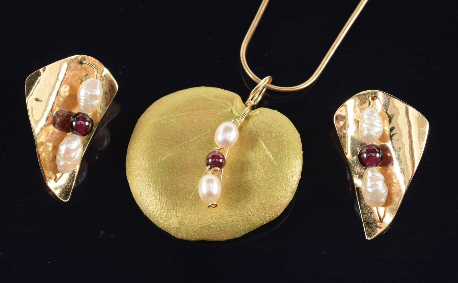 14K gold pearl and garnet jewelry. To include: 1) Pair of 14K earrings with garnet beads and seed: 14K gold pearl and garnet jewelry. To include: 1) Pair of 14K earrings with garnet beads and seed pearls. 2) Similar pearl and garnet bead mounted life-like gold leaf lily pad. Signed Worth on reverse