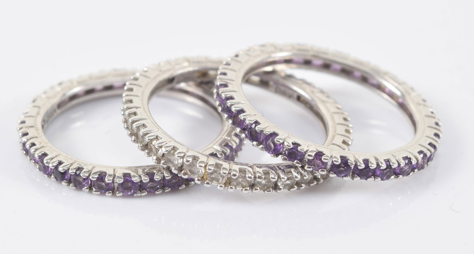 3 sterling silver eternity rings, 2 with amethyst and 1 with topaz. Each marked. Ring size 9.: 3 sterling silver eternity rings, 2 with amethyst and 1 with topaz. Each marked. Ring size 9.