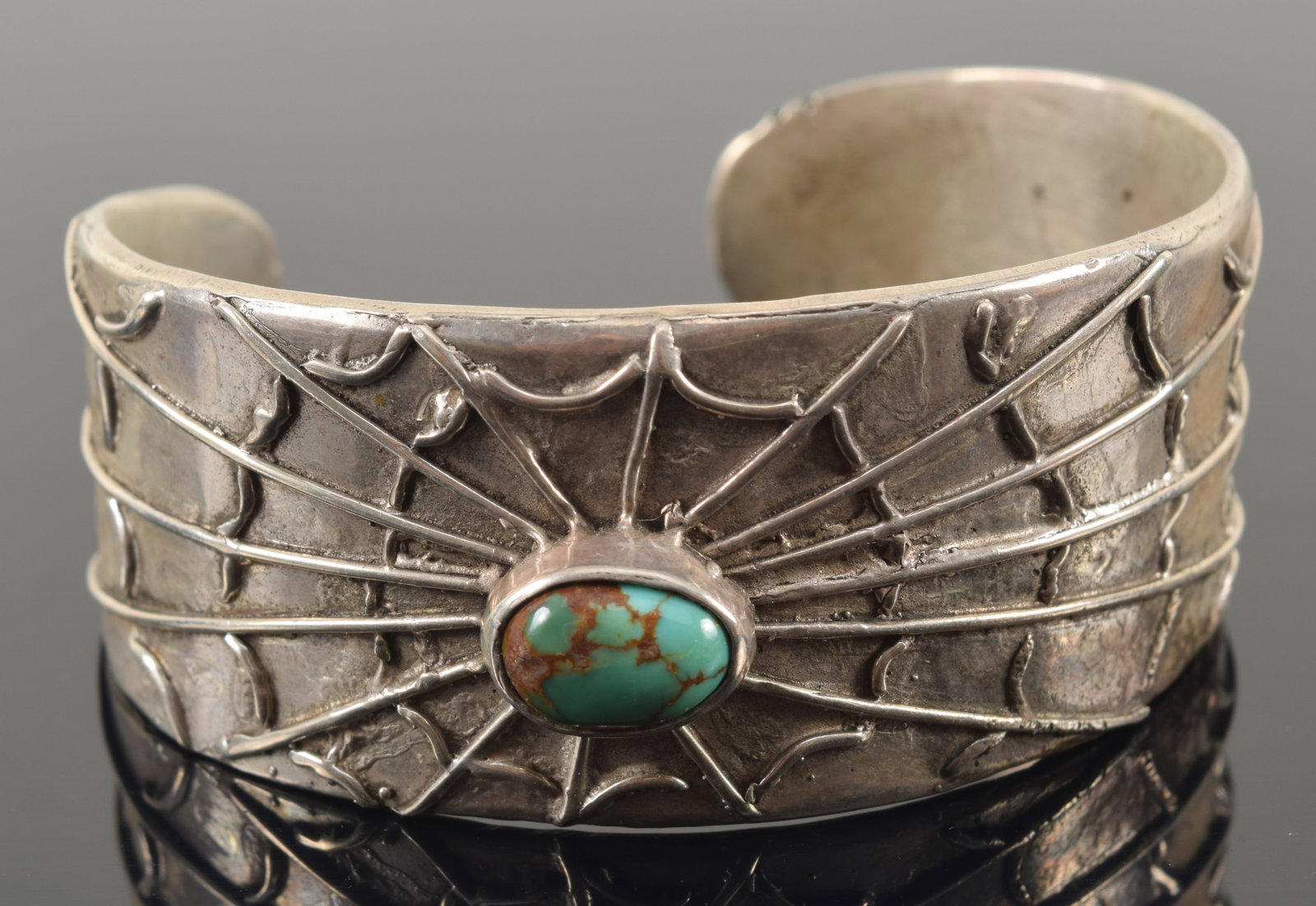 Southwest Native American silver cuff bracelet with spider web design and mounted with a single: Southwest Native American silver cuff bracelet with spider web design and mounted with a single turquoise oval cabochon. Unmarked. 2 3/8in wide. 1.8 ozt.