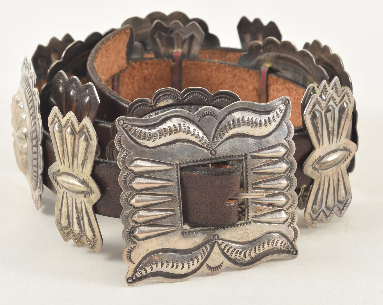 Southwest Native American silver concho belt, early/mid 20th century. Square buckle with alternating: Southwest Native American silver concho belt, early/mid 20th century. Square buckle with alternating pattern of bow-ties and oval medallions. Buckle: 3 x 2.75in. 39in length overall.