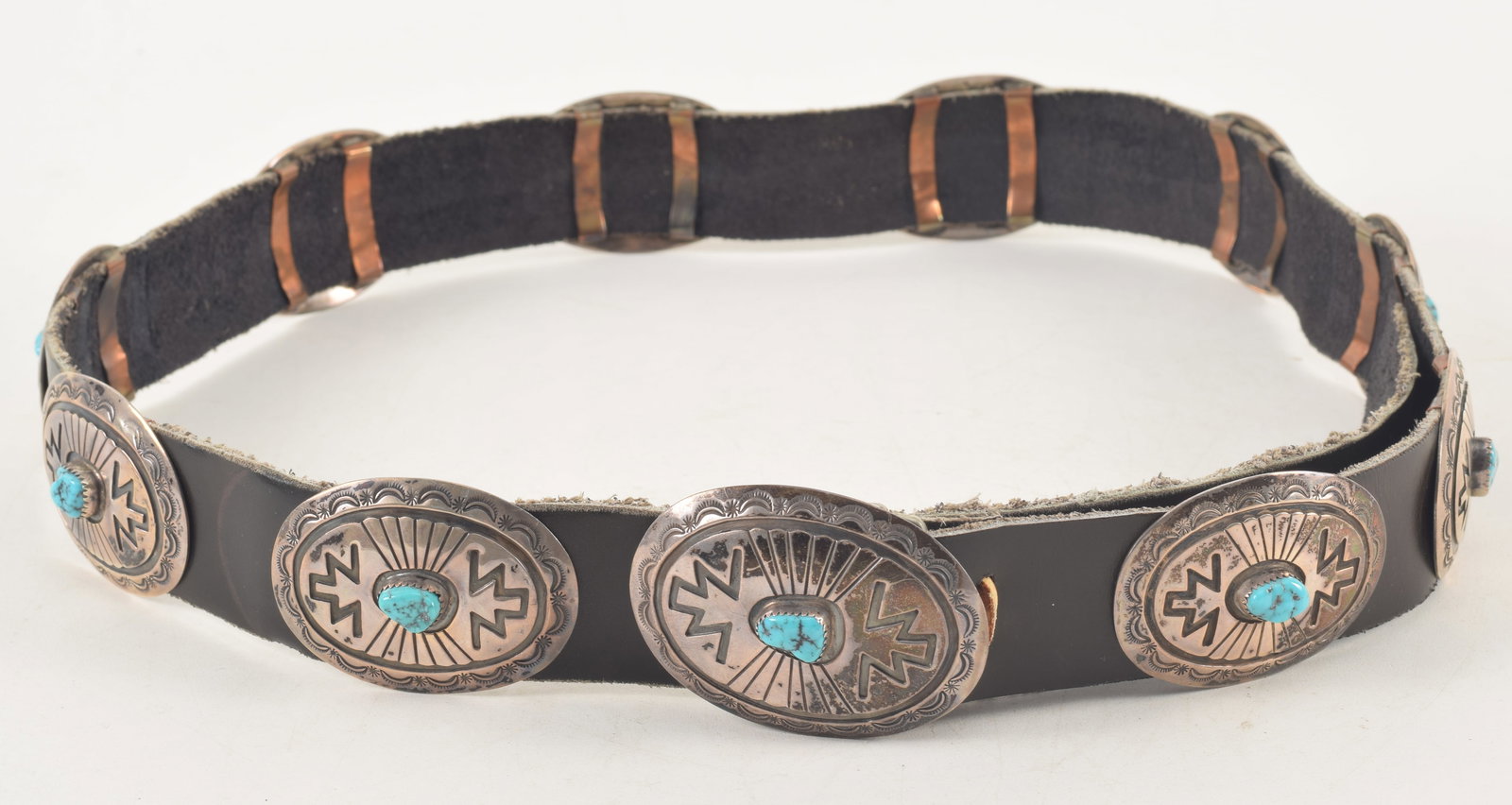 Southwest Native American silver and turquoise concho belt. Recessed and engraved geometric designs: Southwest Native American silver and turquoise concho belt. Recessed and engraved geometric designs with a single central turquoise stone. Buckle: 2 1/2 x 1 7/8in; all others: 2 1/4 x 1 5/8in. Overall