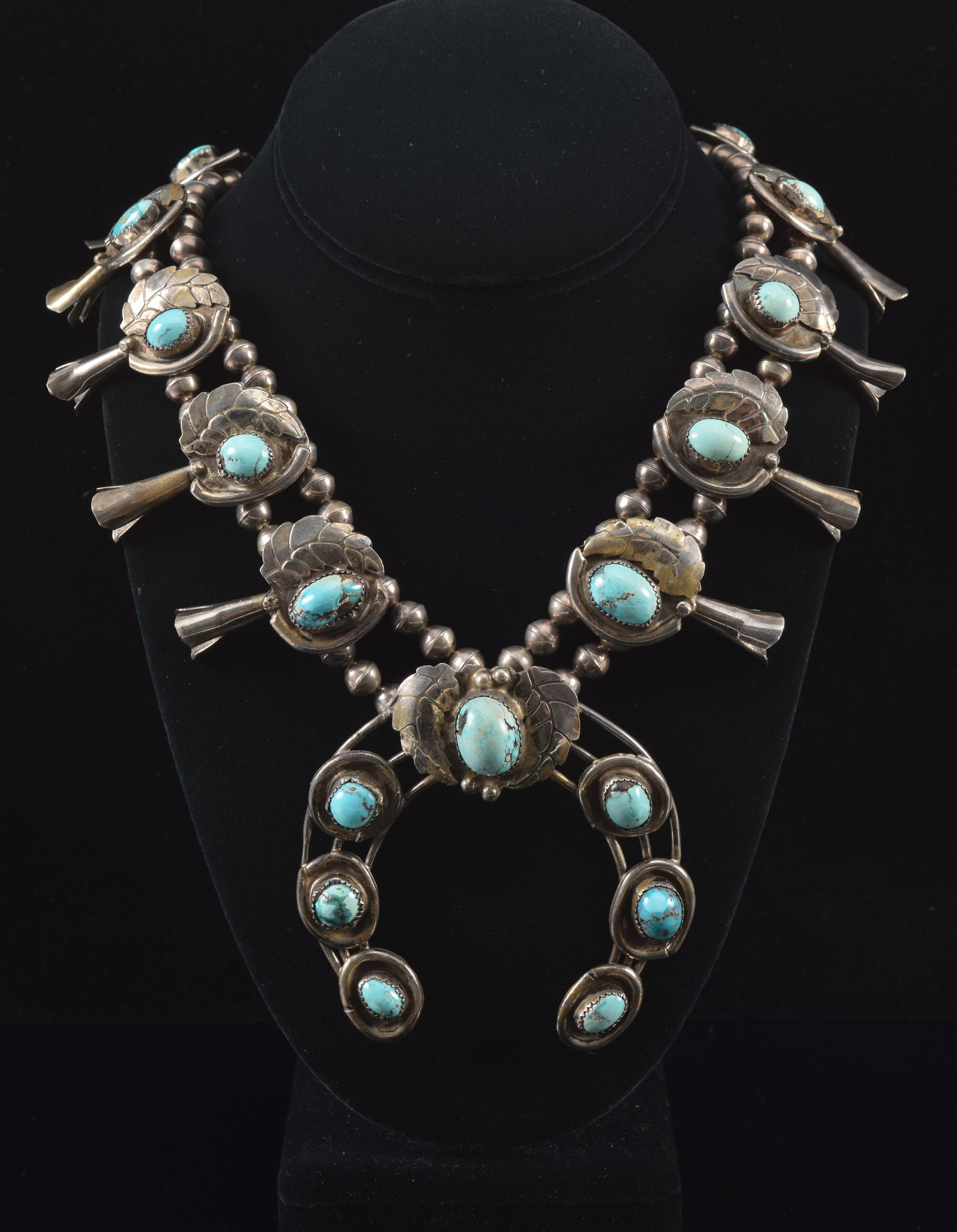 Early Southwest Native American silver and turquoise squash blossom necklace. Leaf and crescent: Early Southwest Native American silver and turquoise squash blossom necklace. Leaf and crescent medallions on the chain terminating with horseshoe shaped pendant with double leaf and bead decoration. 
