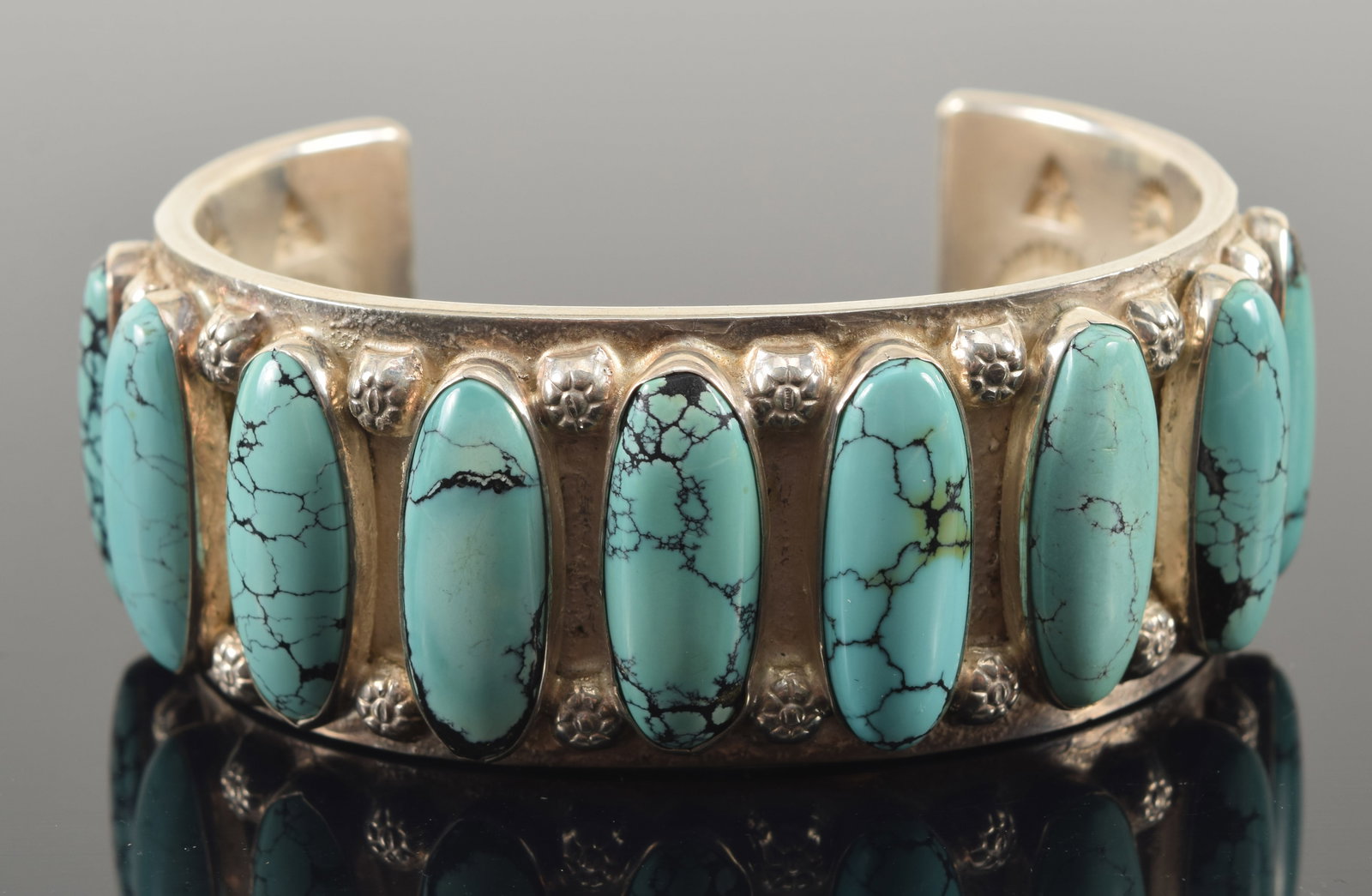 Jimmy Calabaza heavy southwest Native American silver cuff bracelet. Mounted with long turquoise: Jimmy Calabaza heavy southwest Native American silver cuff bracelet. Mounted with long turquoise stones and an orange and purple agate(?) stone on each end. Marked Ca'Win on interior. 2.75in wide. 3.4