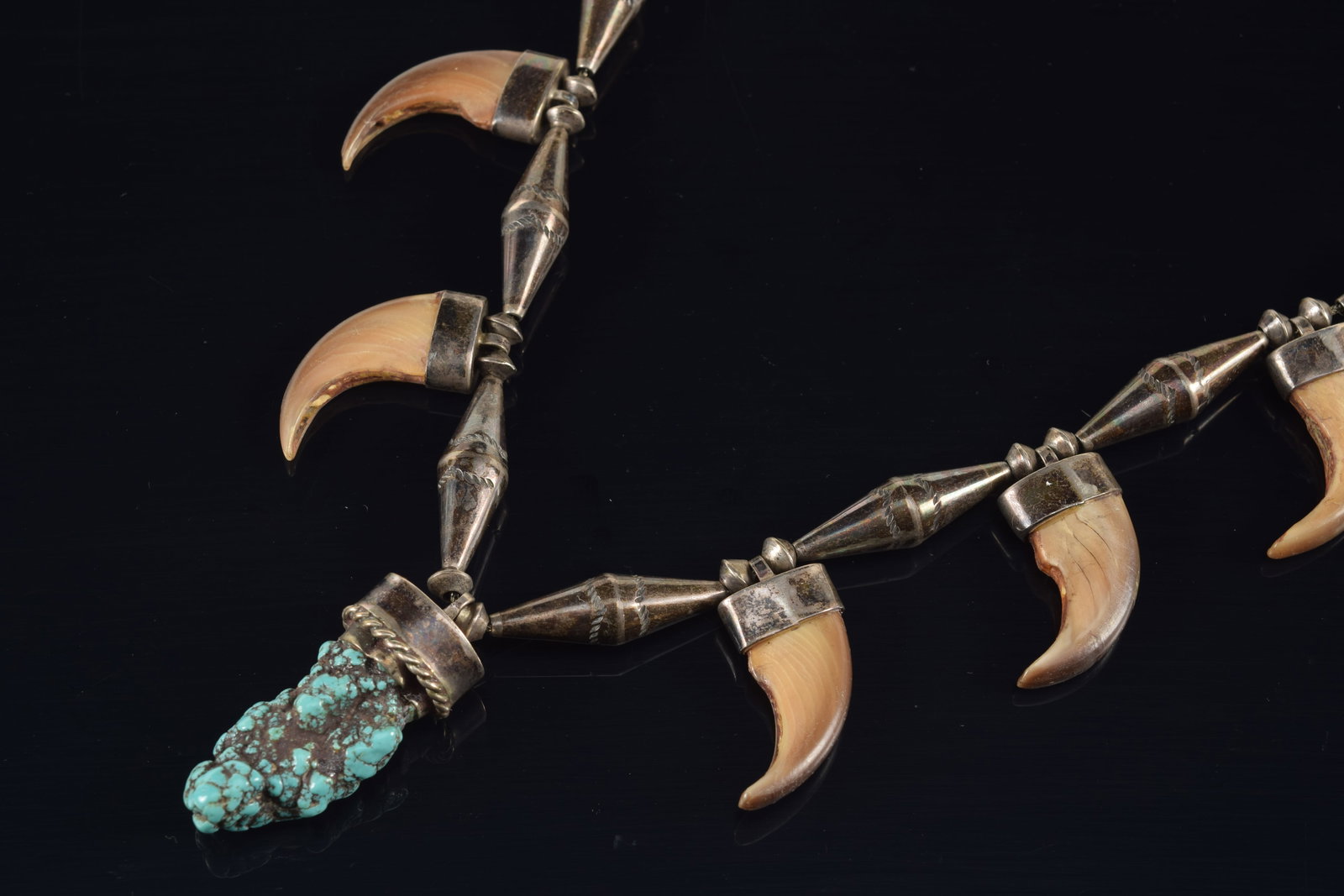 Vintage Native American silver bear claw mounted necklace with turquoise pendant. Set with 12 bear: Vintage Native American silver bear claw mounted necklace with turquoise pendant. Set with 12 bear claws on a chain of tapered cylindrical beads. Necklace length: 27in. 3.5 ozt.
