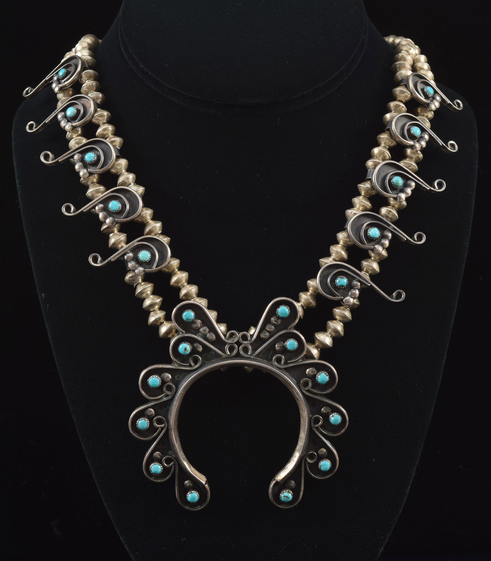 Southwest Native American silver and turquoise squash blossom style necklace. Scrolling wirework: Southwest Native American silver and turquoise squash blossom style necklace. Scrolling wirework design on pendant and accents set with round turquoise stones. Silver disc beads. 22in length. 2.6 ozt.
