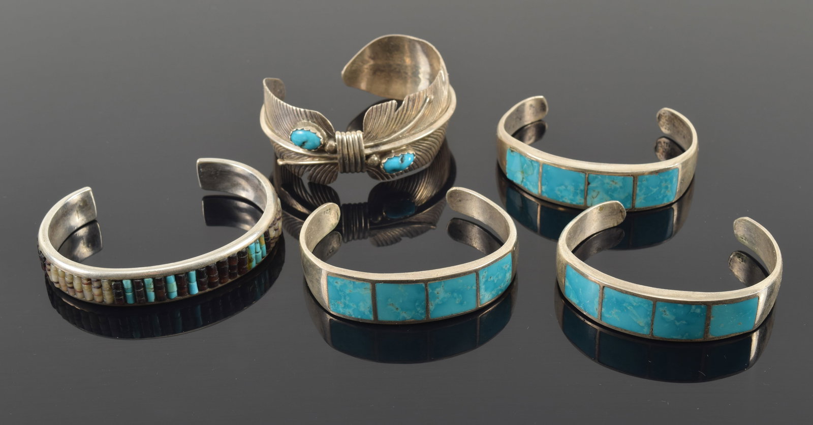 Lot of 5 southwestern sterling silver and turquoise mounted cuff bracelets. 1) Feather form marked: Lot of 5 southwestern sterling silver and turquoise mounted cuff bracelets. 1) Feather form marked sterling and maker's mark of "V". 2) 3 heavy sterling bracelets with 4 square turquoise stones (one w