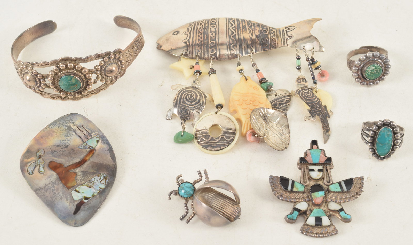 Lot of southwestern and modern silver jewelry. To include: Silver Arrow turquoise cuff bracelet,: Lot of southwestern and modern silver jewelry. To include: Silver Arrow turquoise cuff bracelet, stone inlaid pins, beetle pin, fish drop brooch, etc. Fish pin: 3.25in wide. 2.6 ozt total weight.