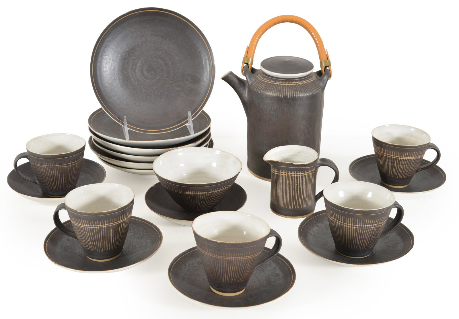 Lucie Rie. England. Mid century modern tea service for six. Dark glaze with sgraffito decoration and: Lucie Rie. England. Mid century modern tea service for six. Dark glaze with sgraffito decoration and artist's cypher stamped on underside. Six tea cups with saucers, 6 plates, handled creamer, open wa