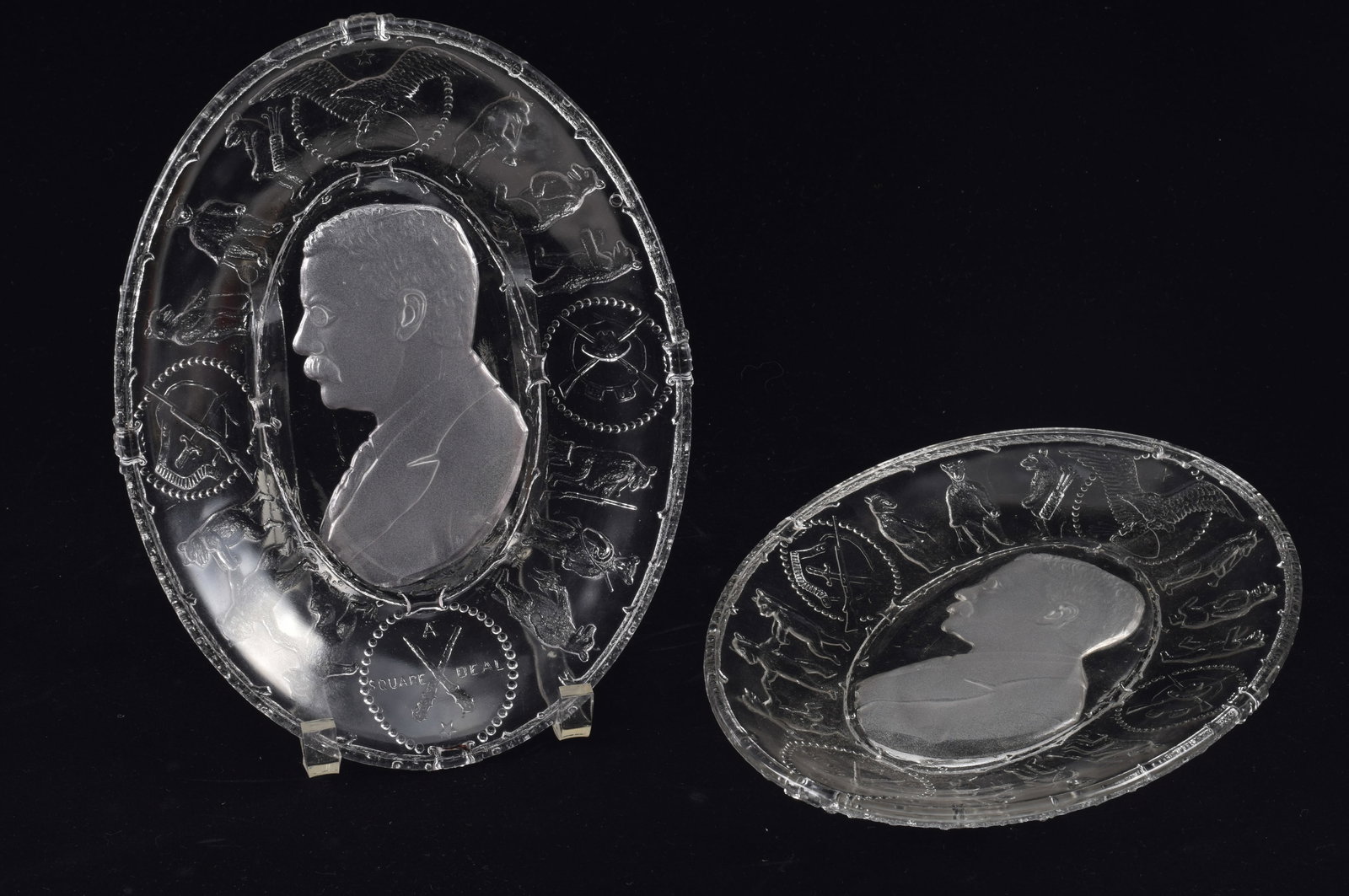 2 Theodore Roosevelt "A Square Deal" pressed glass dishes. Each with a reverse relief bust portrait: 2 Theodore Roosevelt "A Square Deal" pressed glass dishes. Each with a reverse relief bust portrait of Teddy Roosevelt surrounded by a ring of "Teddy" bears in various activities associated with the p
