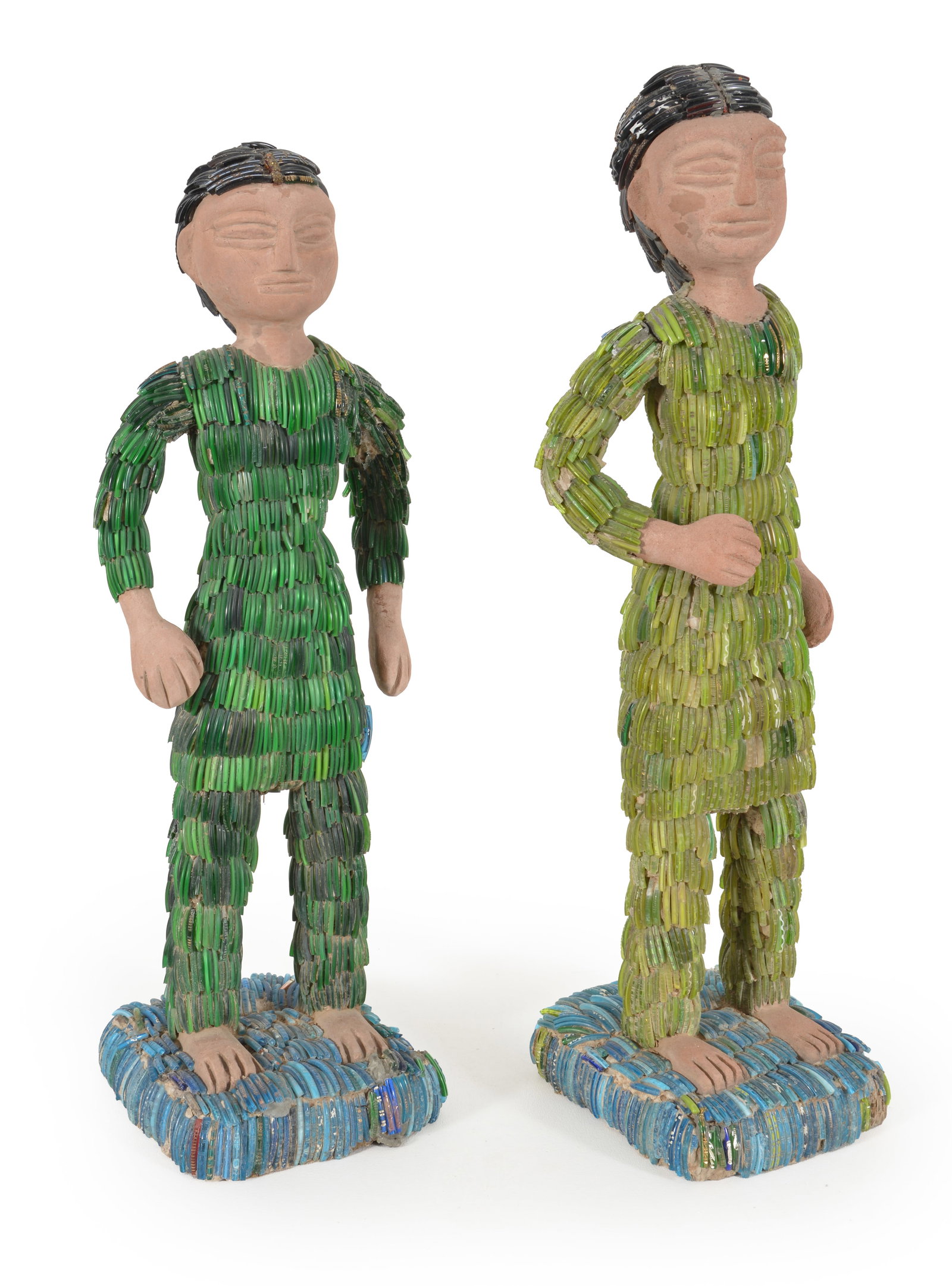 Nek Chand. India. 1924-2015. Concrete, pigment and colored glass rods. 2 Standing figures with black: Nek Chand. India. 1924-2015. Concrete, pigment and colored glass rods. 2 Standing figures with black hair and green garments on a blue ground. Heights 21 in and 19 1/2 in.