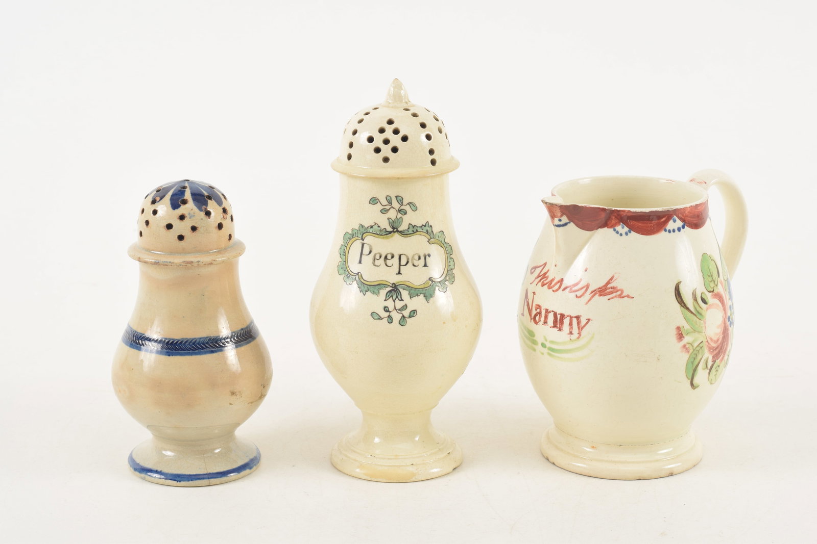 3 Leeds creamware items, including a floral decorated cream pitcher and 2 shakers, one marked: 3 Leeds creamware items, including a floral decorated cream pitcher and 2 shakers, one marked "Peeper". Heights 4 1/2, 6 and 4 1/2 in.
