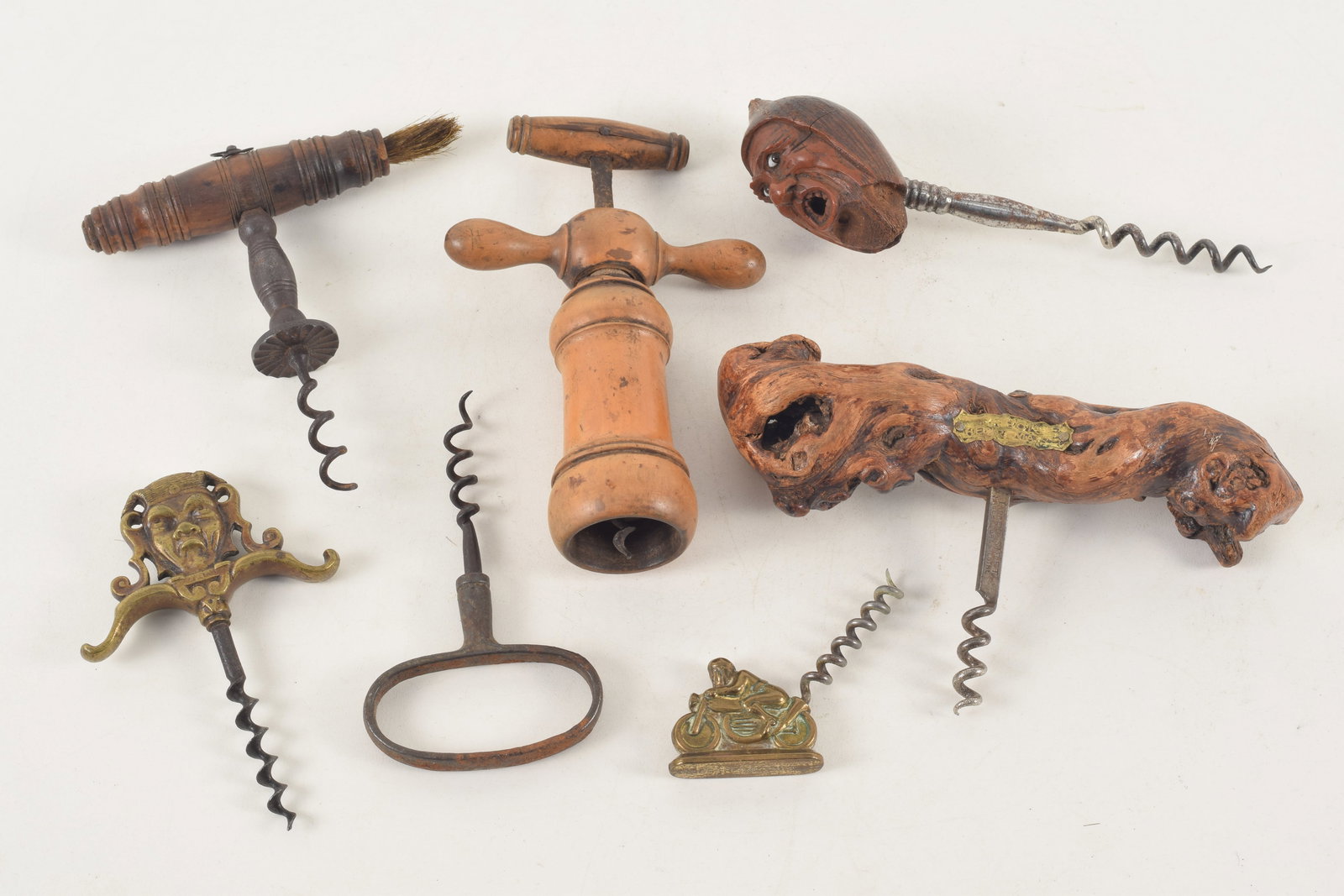 Collection of antique corkscrews including carved nut, burlwood signed Henri Maire, cast figural: Collection of antique corkscrews including carved nut, burlwood signed Henri Maire, cast figural jester and motorcycle and treenware. Largest: 7in wide.