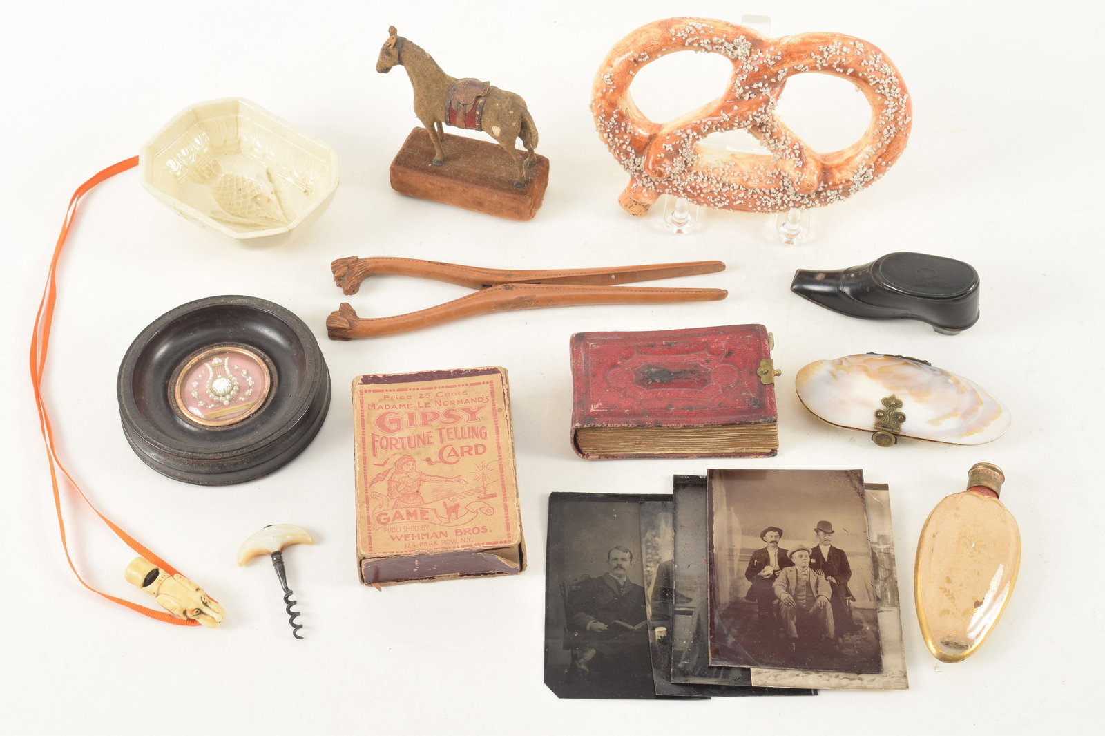 A collection of antique curiosities, including a beaded reliquary, pudding mold, playing cards,: A collection of antique curiosities, including a beaded reliquary, pudding mold, playing cards, shell form coin purse, scent bottle, card dog form whistle, boot form snuff box, pretzel form whiskey fl