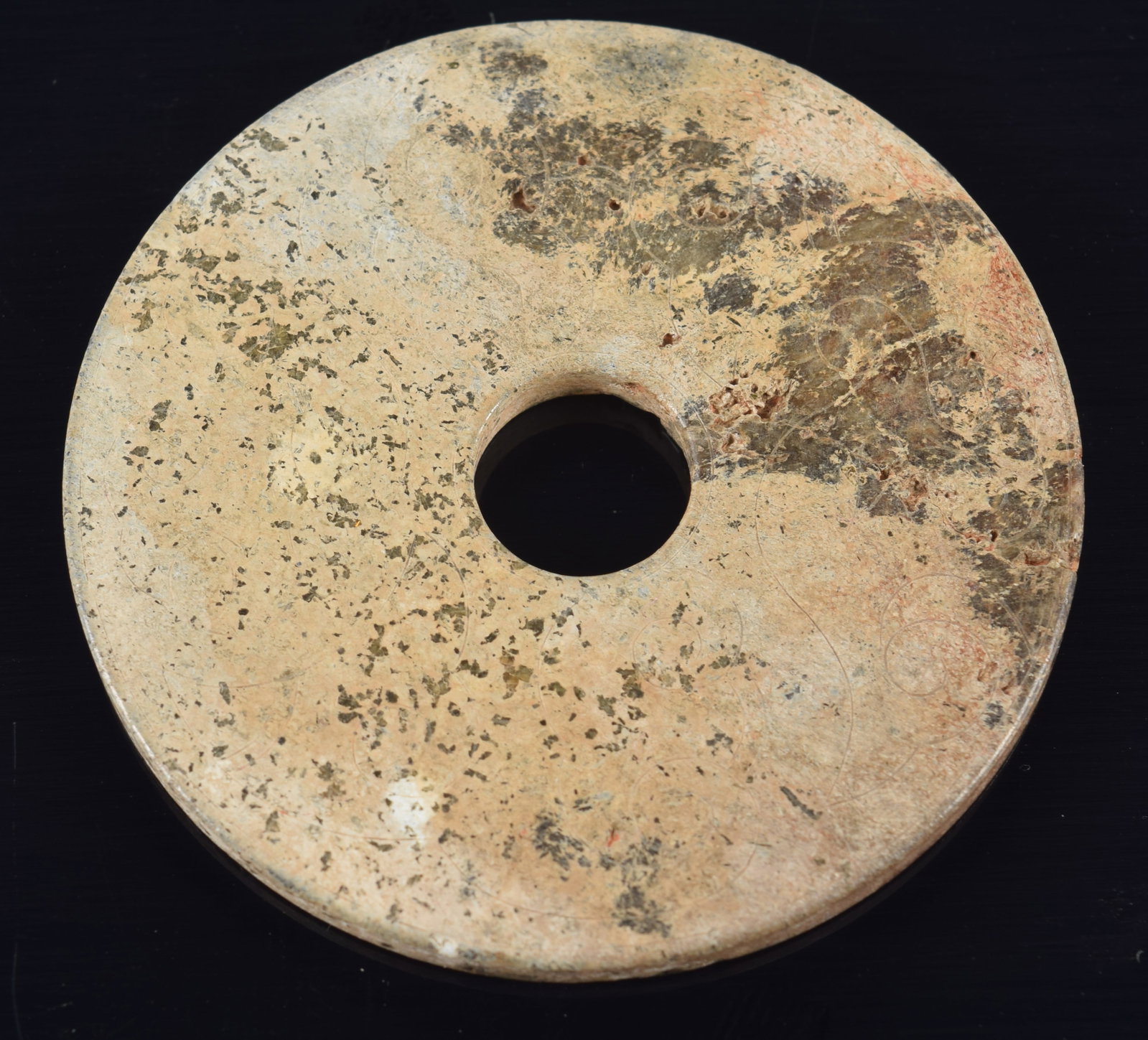 Jade pi disc. China. Archaic incised decoration. Calcified dark green stone. 2 1/8in diameter. (1 of 2)