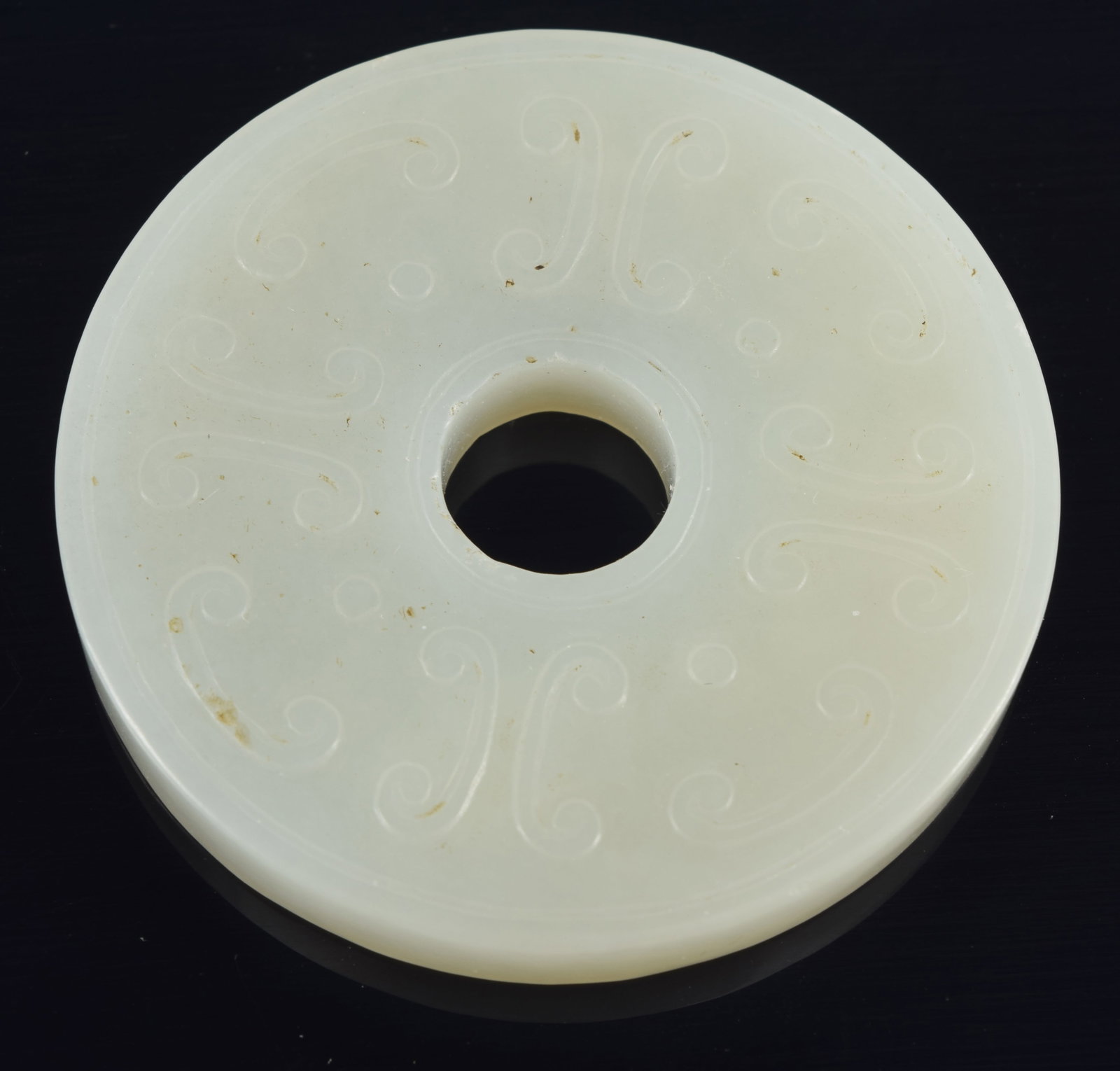 Jade pi disc. China. 19th century. Pale celadon/white stone carved with archaic scrolling. 2in (1 of 4)