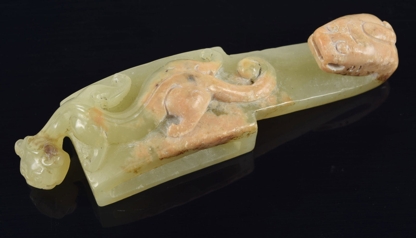 Jade garment hook. China. 19th century or earlier. Surface carved with dragons. Reverse with: Jade garment hook. China. 19th century or earlier. Surface carved with dragons. Reverse with inscription. Stone a celadon color with skin. 3.5in length.