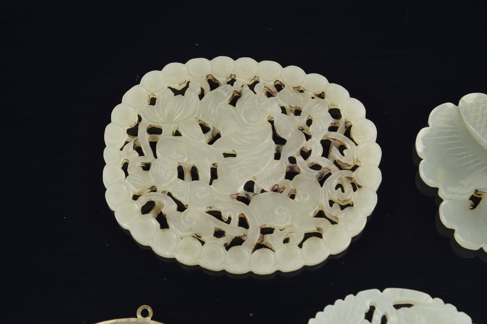 4 jade pendants. China. 19th to early 20th century. One silver mounted. 3in. - 2