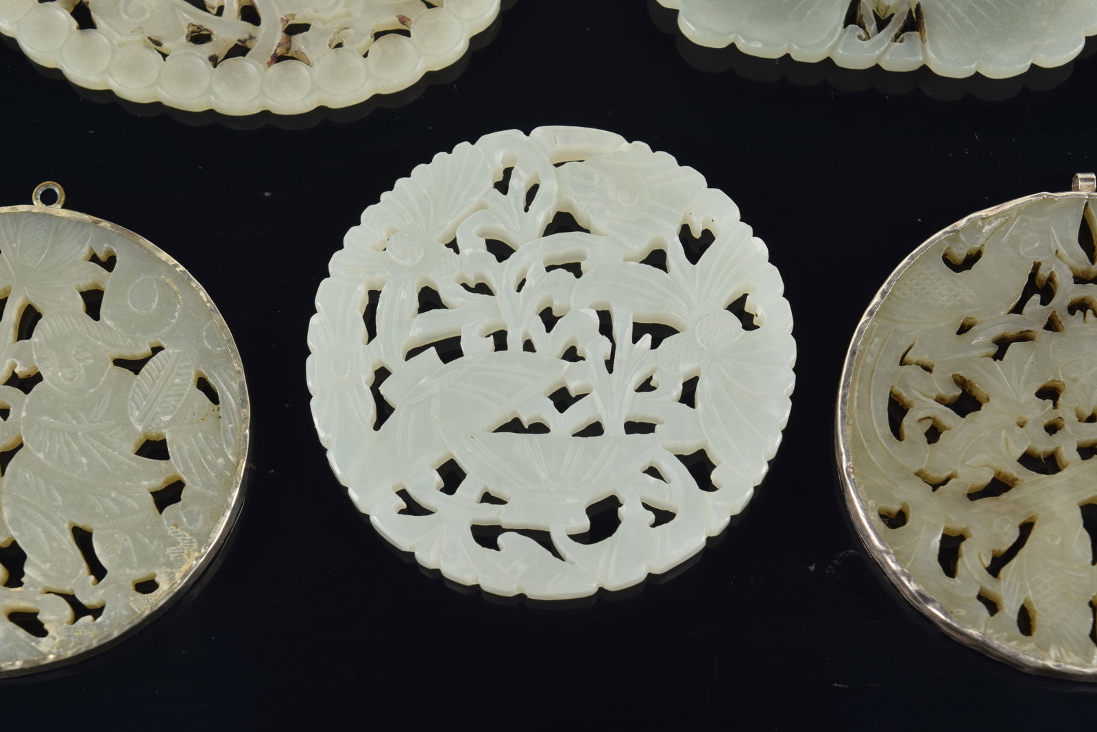 4 jade pendants. China. 19th to early 20th century. One silver mounted. 3in. - 4