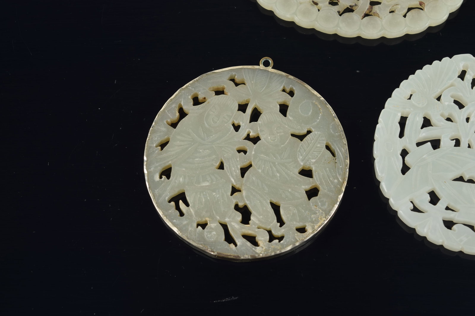 4 jade pendants. China. 19th to early 20th century. One silver mounted. 3in. - 6