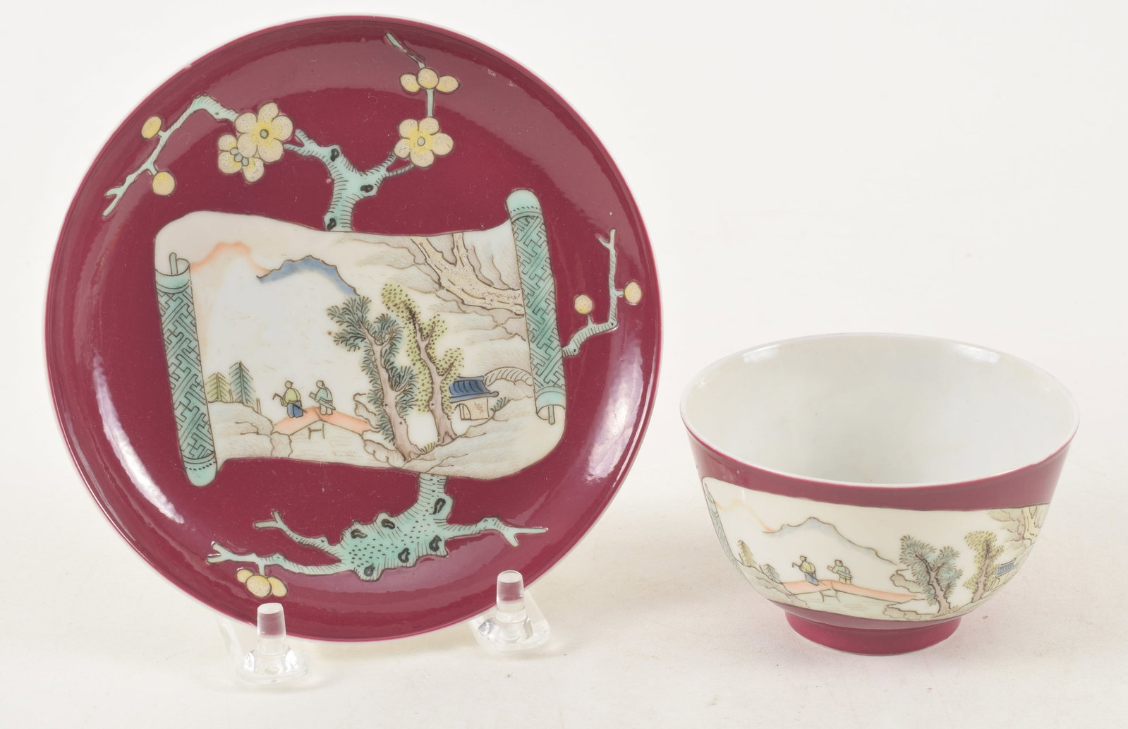 Porcelain cup and saucer. China. 18th century. Ruby ground with famille rose decoration of a fan and: Porcelain cup and saucer. China. 18th century. Ruby ground with famille rose decoration of a fan and flowering peonies.