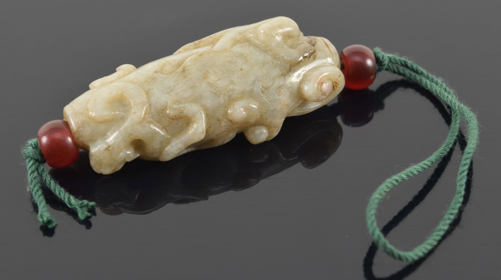 Jade pendant. China. 19th century or earlier. Surfaced relief carved with dragons and scrolling. (1 of 2)