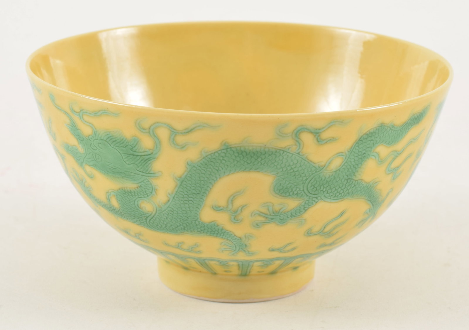 20th century Chinese yellow ground footed porcelain bowl. Green stippled dragon and phoenix: 20th century Chinese yellow ground footed porcelain bowl. Green stippled dragon and phoenix decoration. Guangxu mark on base. 4.5in wide.