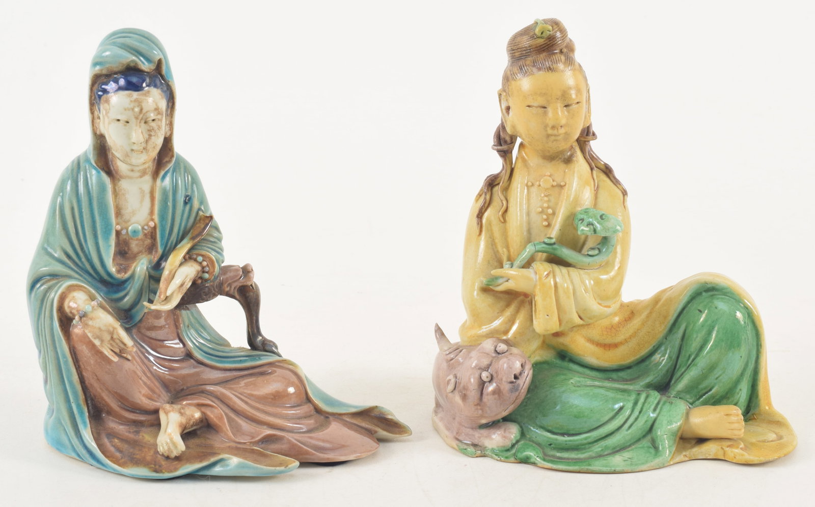 2 19th century or earlier Chinese porcelain seated Guanyin figures. 1) Yellow glaze with aubergine: 2 19th century or earlier Chinese porcelain seated Guanyin figures. 1) Yellow glaze with aubergine glaze beast. 2) Blue robed figure with losses to scepter and fingers. Impressed seal. Each about 5.75