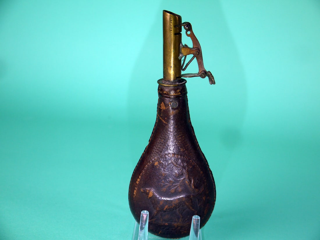 EARLY SHOT DISPENSER, AMERICAN FLASK AND CAP CO.: VERY EARLY SHOT DISPENSER by the American Flask and Cap Company (1857-1865). Very good original condition consistent with age. Leather pouch features a hunting dog design on front and back. "2 1/2
