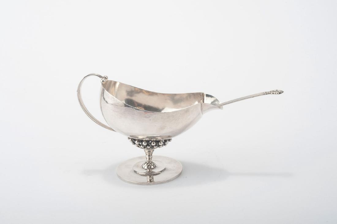'43' creamer with spoon, 1908: H. 11.8 cm; L. 17.5 cm. Designed by Johan Rohde. Made past 1945. Silver. Marked: DESSIN JR, DENMARK, GEORG JENSEN (beads), STERLING, 43 resp. STERLING DENMARK, GEORG JENSEN (beads).