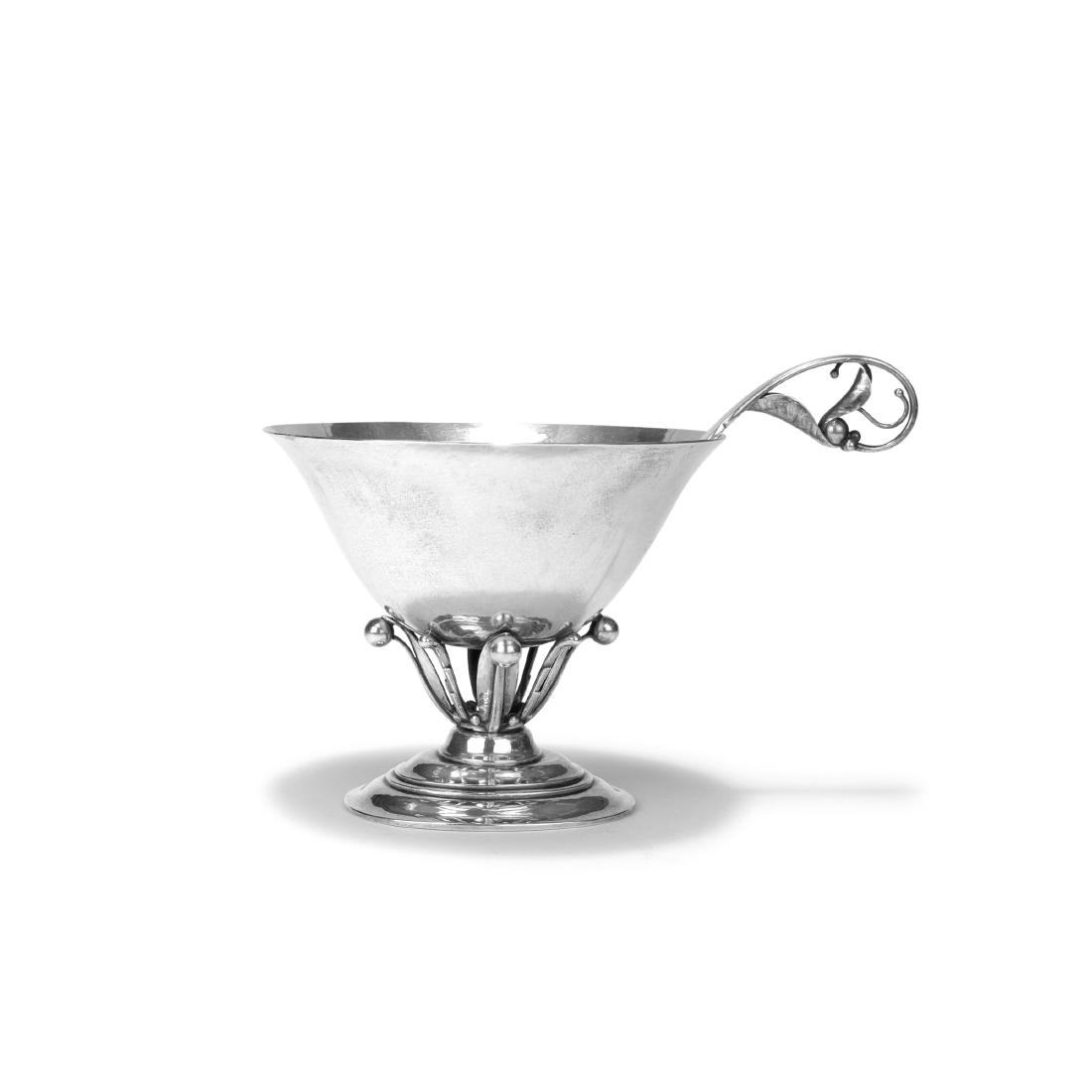 Footed bowl with spoon, c1915: Johan Rohde e.a., Bowl: H. 13.4 cm; D. 16 cm; spoon: L. 20 cm. Made by Georg Jensen, Copenhagen, 1909-14 resp. 1936-30. Silver. Marked: DESSIN JR, GEORG JENSEN (beads with crown), DENMARK, GI 925 S, S