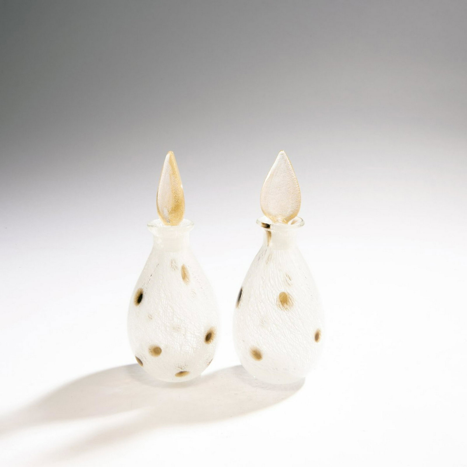 A. Seguso, Two flacons 'Merletto pois', 1954: A. Seguso, Two flacons 'Merletto pois', 1954, Drop-shaped with leaf-shaped plug. H. 18.5-19 cm. Execution: Vetreria Archimede Seguso. Cased glass, colorless, fused ribbons with white 'merletto' thread