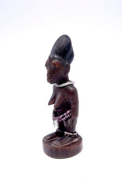 Yoruba: Nigeria, Yoruba. Ibedji figure. Female, with scarification marks. Wood with remains of red and blue pigmentation, small iron nails to mark the pupils. Different chains of glassbeads. H. 23 cm.Provenan