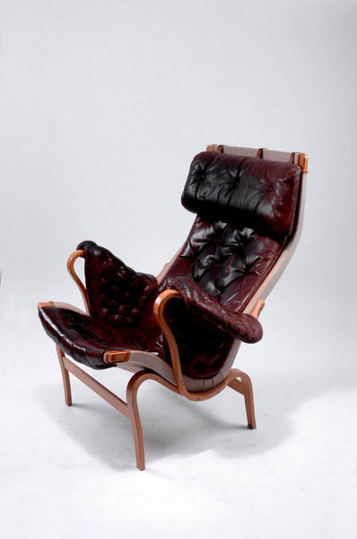 Mathsson, Bruno: Bruno Mathsson. 'Pernilla 2' armchair with cushions, designed in 1944. H. 96.5 x 92 x 82.5 cm. Made by Dux International AB. Birch plywood, brown straps, dark-brown leather upholstery with headrest. M