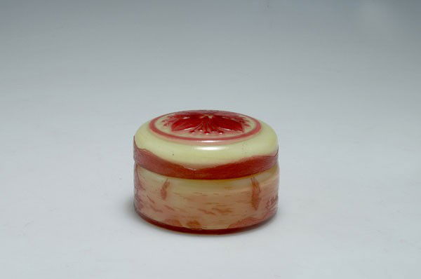 Michel, Nancy. Covered box with coastal landscape, 1915: Michel, Nancy. Covered box with coastal landscape, 1915-20. H. 7 cm; Diameter 9 cm. Cased glass, clear, yellow and red. Etched pattern with sailboats in front of a rocky coast. Cover with flowers. Sig