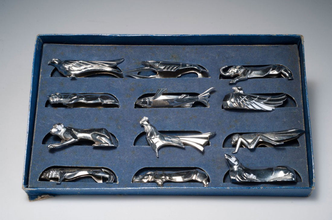 Zwolf Messerbankchen, um 1925: Christofle, Paris (attributed). Twelve kniferests, circa 1925. L. 7.8-10.4 cm. Silver-plated metal.