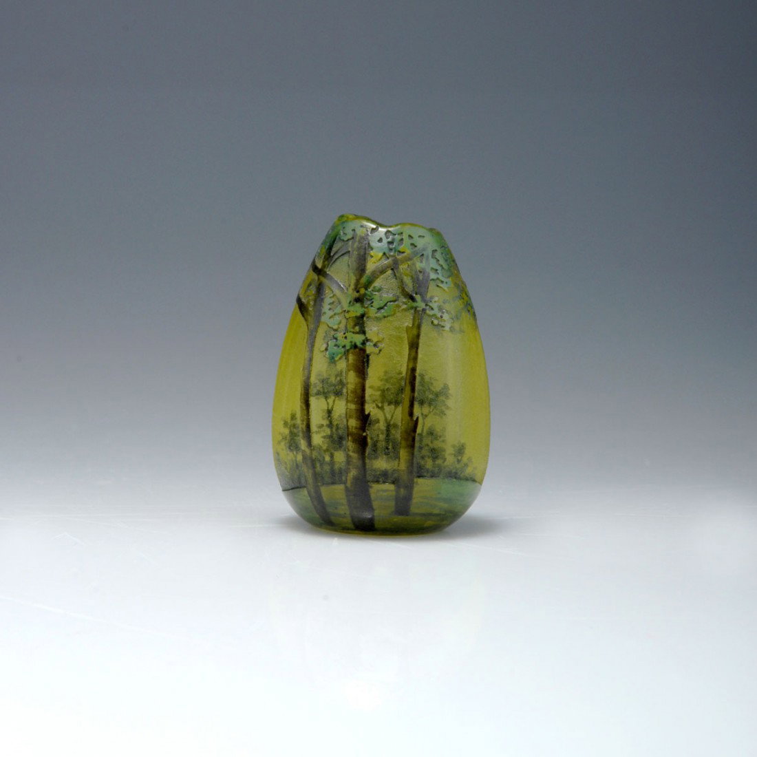 Miniaturvase 'Arbres en ete', 1903-05: Daum Freres, Nancy. Miniature 'Arbres en ete' vase, 1903-05. H. 4.6 cm. Cased glass, clear, yellow powder inclusions, green enamel fusions. Etched pattern, Grisaille paint. Wood in summer. Signed: Dau