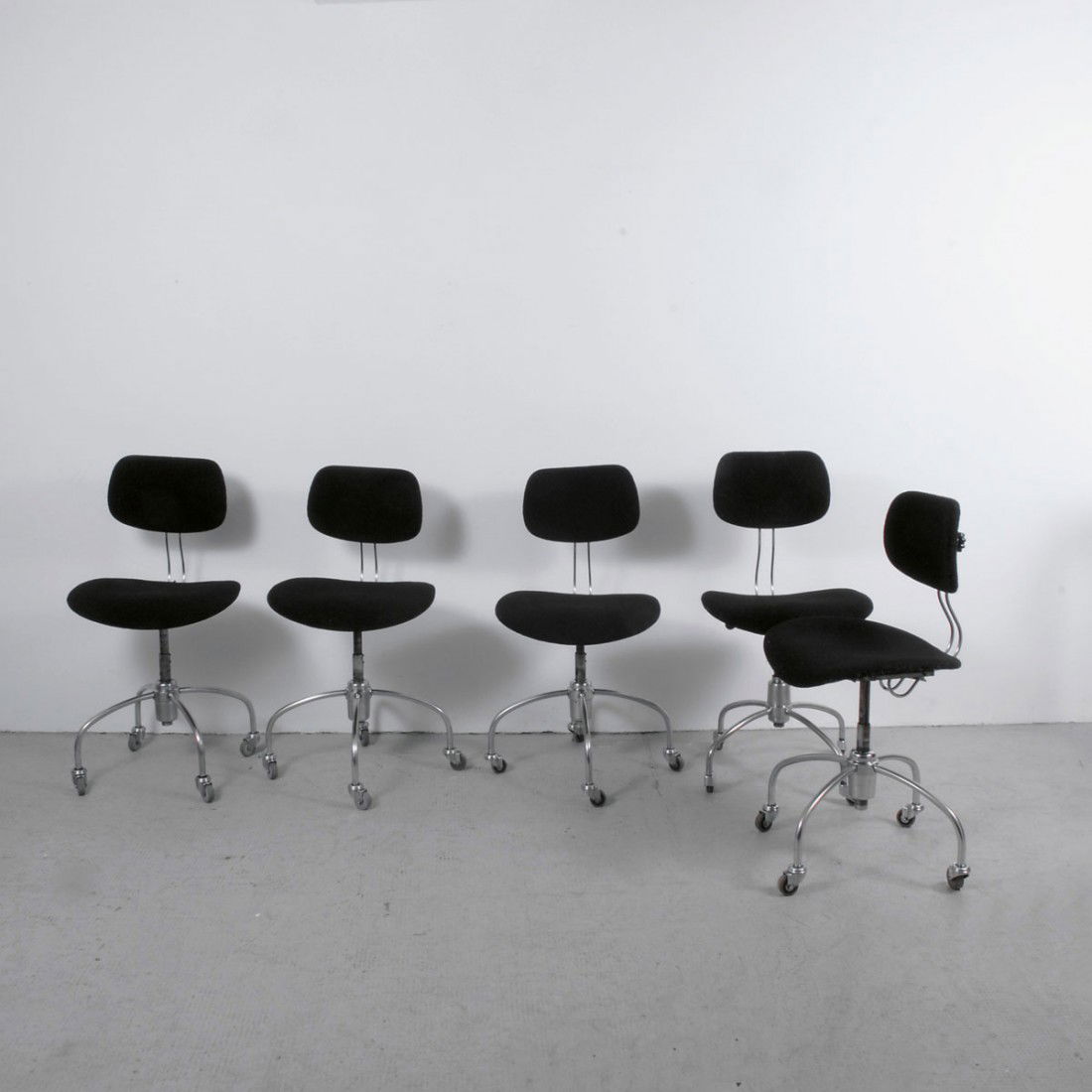 Fuenf Arbeitsstuehle auf Rollen 'SE-40 R': Egon Eiermann. Five 'SE-40 R'desk chairs on wheels, designed in 1953/54. H. 86.5 x 47.5 x 46 cm. Made by Wilde & Spieth, Esslingen. Plywood shells with black upholstery, nickel-plated tubular steel ba