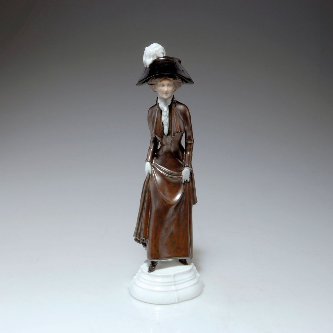 Dame mit Hut, um 1910: Bing & Gröndahl, Copenhagen. Lady wearing a hat, c1910. H. 20.4 cm. Porcelain, white, glazed, overglaze in brown and black. Marked: Maker's mark, B&G, 1734, H-S, further marking.