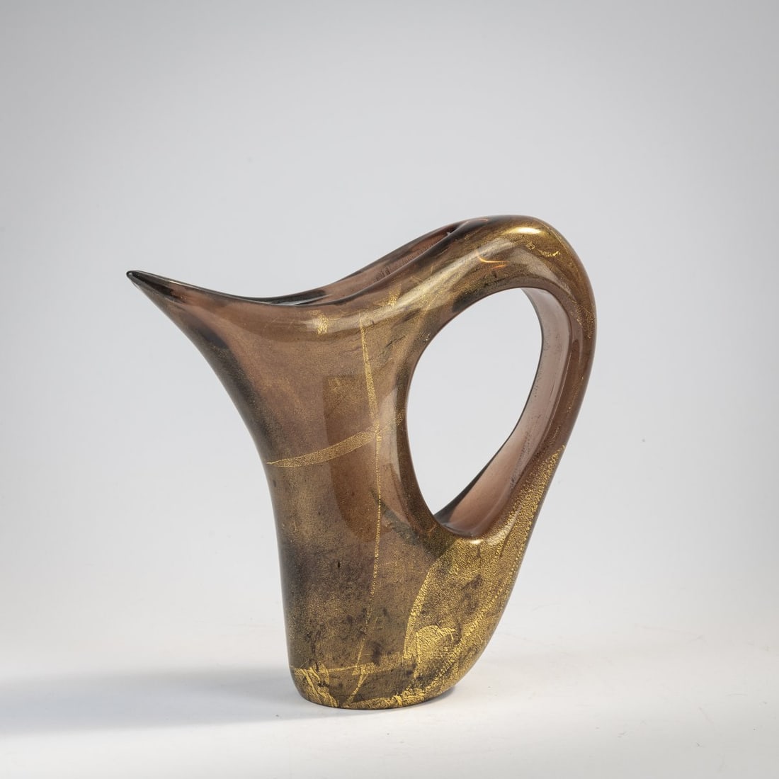 Giorgio Ferro, 'Anse volante' vase, c. 1952: H. 23 cm. Execution: A.Ve.M. Thick-walled glass, brown with bursted gold foil, slightly iridescent.