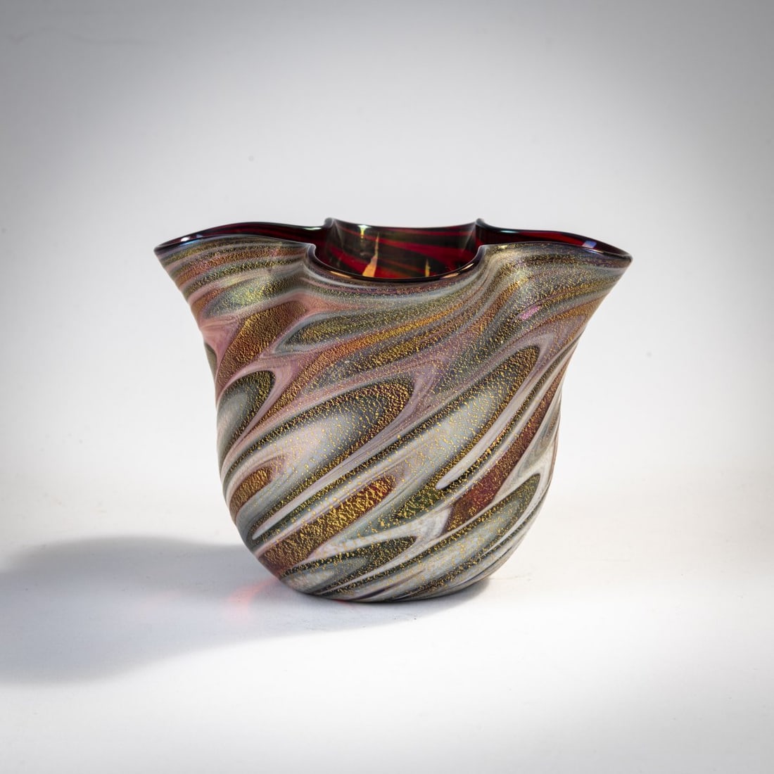Gino Cenedese, 'Variegato' vase, 1950: H. 10.7 cm. Cased glass, red, with streaky fusions in opaque white and gray, burst gold foil, iridescent. Literature: Marina Barovier, Rosa Barovier Mentasti, Attilia Dorigato, Il Vetro di Murano all