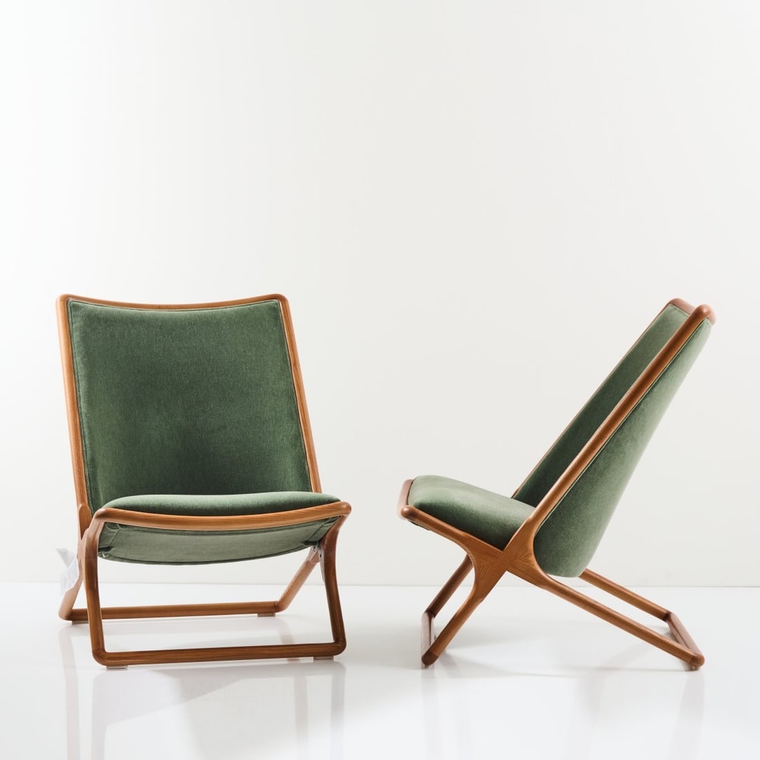 Ward Bennett, Two 'Scissor Chair' lounge chairs, 1960s: H. 85 x 61 x 73 cm. Made by Herman Miller, Zeeland, MI, 2022. Ash wood, stained dark, green velvet wool mohair cover. Marked: manufacturer's tag.