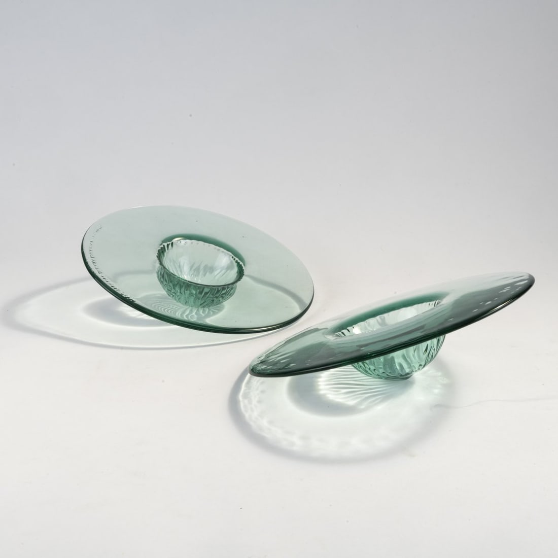Philippe Starck, Two 'Peninsula' fruit bowls, 1994: Ø 25 cm. Made by CIVE, Italy. Green-tinted glass, partly in relief. Marked: STARCK for THE PENINSULA PREMIERE December 1, 1994 (embossed).