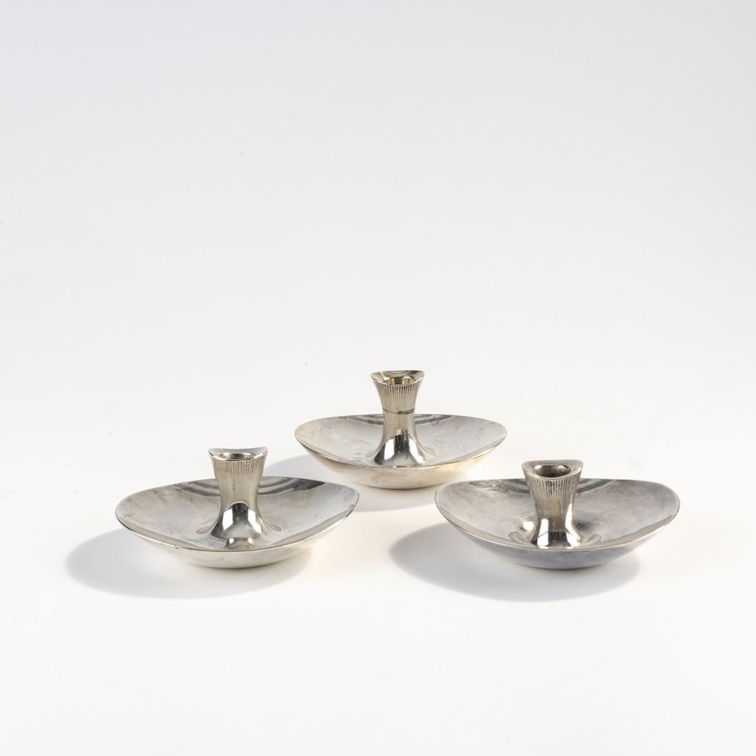 Tapio Wirkkala, Three candlesticks, c. 1956: H. 5 x 11 x 12.5 cm. Made by Kultakeskus Oy, Hämeenlinna, in 1968 and in Helsinki, in 1956. Silver. Marked: manufacturer's mark, crown mark, 813H and 916H, city mark, P7 and C7, artist's signet T