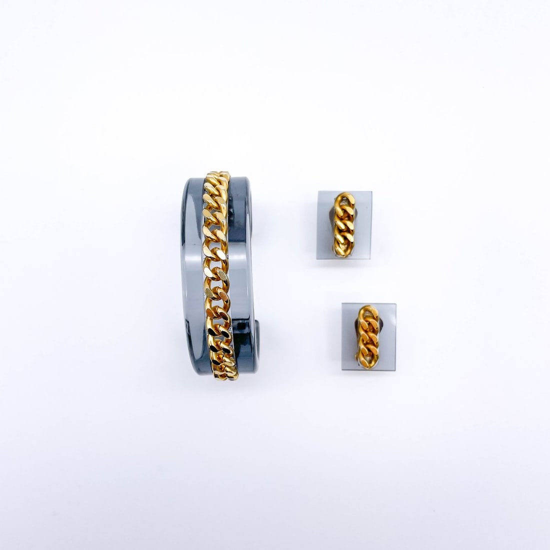 Guy Laroche, Two-piece Vintage jewelry set: Consisting of bangle and clip earrings. Gray tinted plastic, gold-colored metal strap. Bangle Ø 5.5 cm (inside); clip earrings H. each 2.5 x 2 cm. Manufacturer's label each.