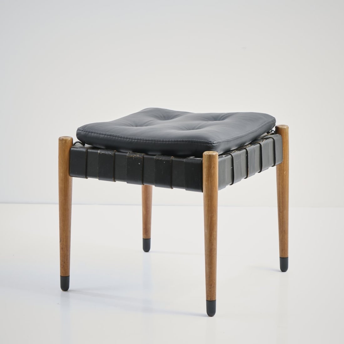 Egon Eiermann, 'SE 120' stool, 1969: H. 47 x 48 x 48 cm. Made by Wilde & Spieth, Esslingen. Beech wood, partially painted black, black leather straps, black leather seat cushion. Literature: Exh. cat. Egon Eiermann, Die Möbel,