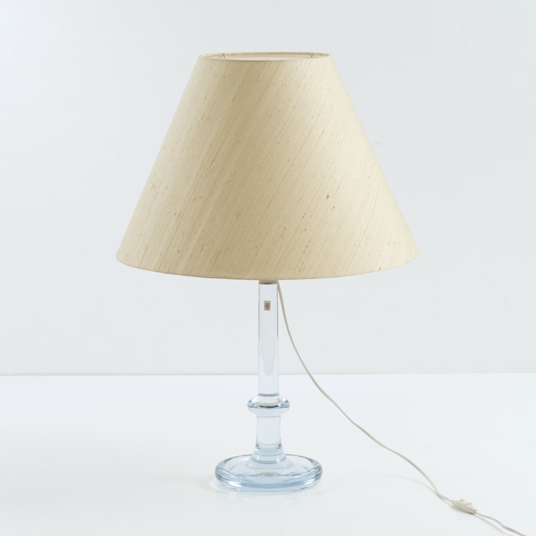 Ingo Maurer (attr.), Table light, 1969: H. 73.5 cm, Ø 35 cm. Made by Design M, Ingo Maurer, Munich (attributed). Clear glass, white fabric shade. Marked: Manufacturer's label (Holmegaard).