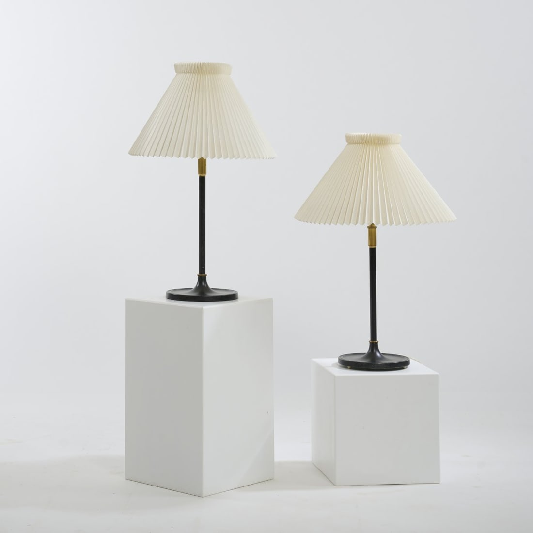 Le Klint, Denmark, Two table lights, 1940s: H. 67-87 cm, Ø 43-46 cm. Plastic, pleated, tubular brass, sheet brass, partly painted black. Marked with makers mark (shade).