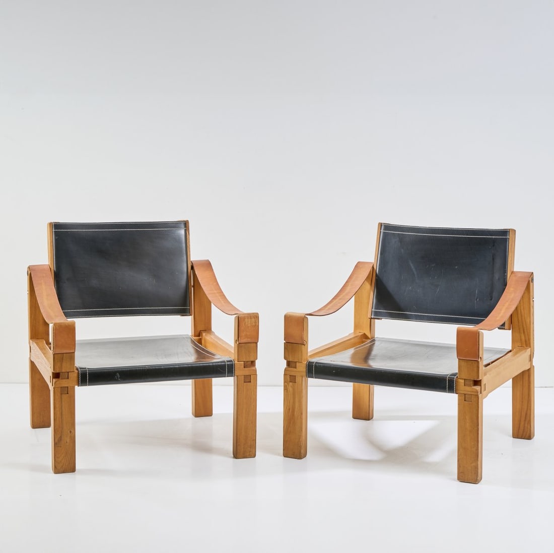 Pierre Chapo, Two 'Cuir - S10X' armchairs, c. 1960: H. 75 x 68 x 68 cm. Made by Chapo Gordes SA, Gordes. Solid elm wood, black and brown leather.