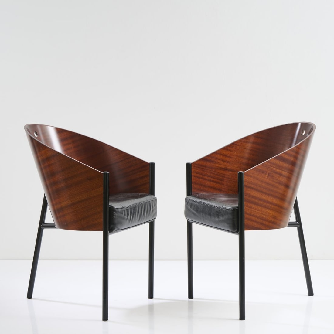 Philippe Starck , Two armchairs 'Costes', 1982: H. 80 x 48 x 60 cm. Made by Driade Aleph, Milan. Plywood with mahagoni veneer, tubular metal, painted black, black leather. Marked: manufacturer's sticker.